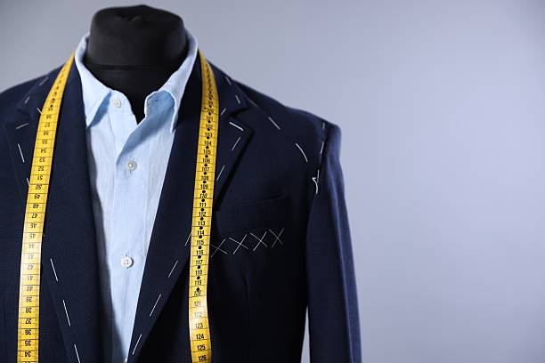 Tailoring concept: jacket and shirt on mannequin with measuring tape, gray backdrop, editable space for text.