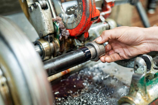 Industrial production scene with a worker using a threading machine, focusing on accuracy and workflow.